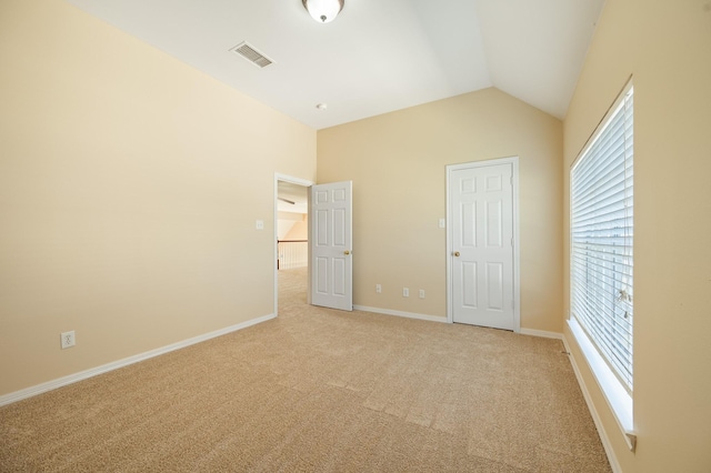 unfurnished bedroom featuring lofted ceiling, light colored carpet, visible vents, and baseboards