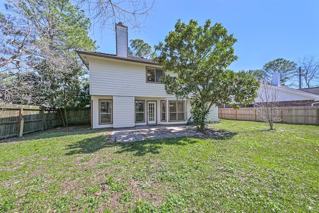 back of property with a patio, a fenced backyard, a lawn, and a chimney