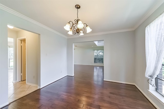 spare room featuring a chandelier, plenty of natural light, ornamental molding, and wood finished floors