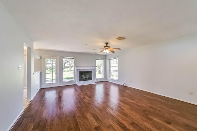 unfurnished living room featuring dark wood finished floors, plenty of natural light, a fireplace, and visible vents