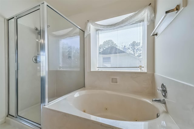 bathroom with a shower stall and a tub with jets