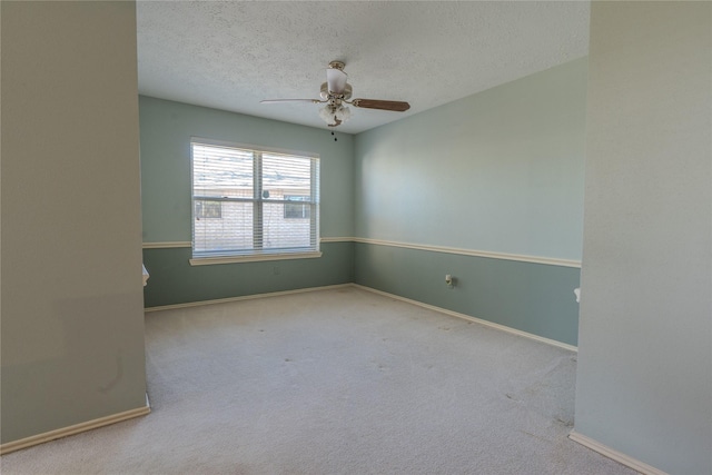 carpeted empty room featuring a textured ceiling, baseboards, and a ceiling fan