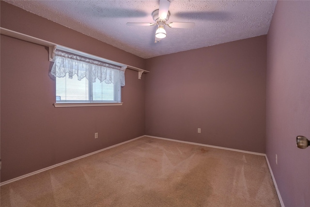 spare room featuring light carpet, a textured ceiling, baseboards, and a ceiling fan