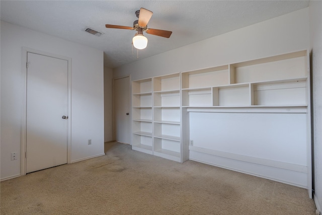 unfurnished bedroom with carpet flooring, a ceiling fan, visible vents, and a textured ceiling