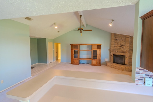 unfurnished living room featuring a ceiling fan, visible vents, lofted ceiling with beams, a textured ceiling, and a brick fireplace