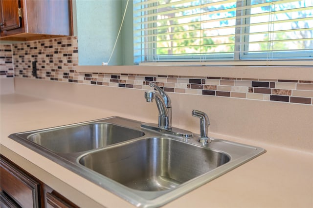 details featuring a sink, decorative backsplash, brown cabinetry, and light countertops