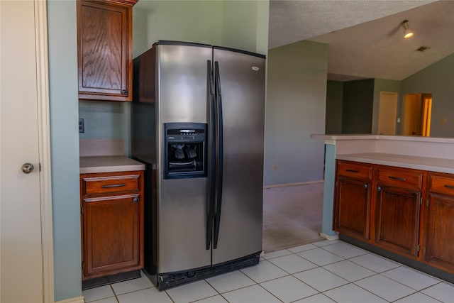 kitchen featuring light countertops, light tile patterned floors, stainless steel fridge, and a textured ceiling