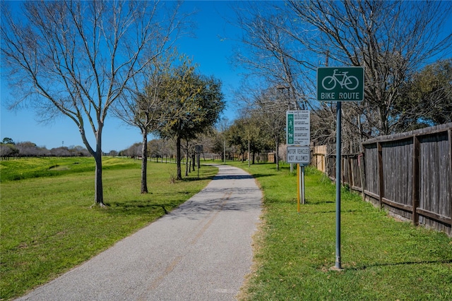 view of community with a yard, fence, and driveway