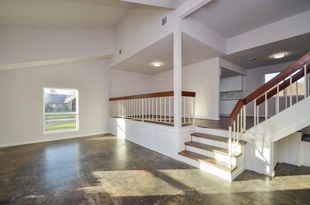 staircase featuring baseboards, a healthy amount of sunlight, visible vents, and finished concrete floors