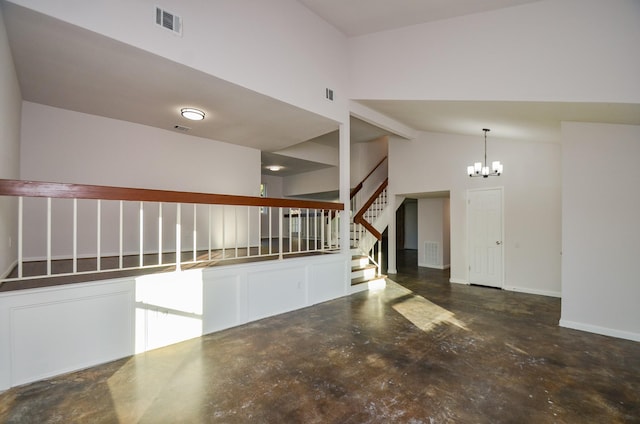 interior space featuring visible vents, concrete floors, baseboards, a chandelier, and stairway