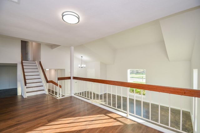 hallway featuring vaulted ceiling, stairway, an inviting chandelier, and wood finished floors