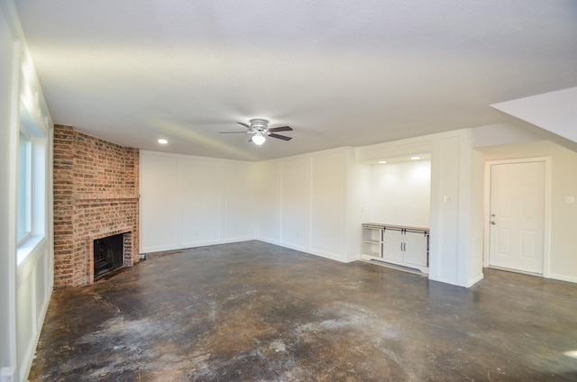 unfurnished living room with a fireplace, concrete floors, and ceiling fan