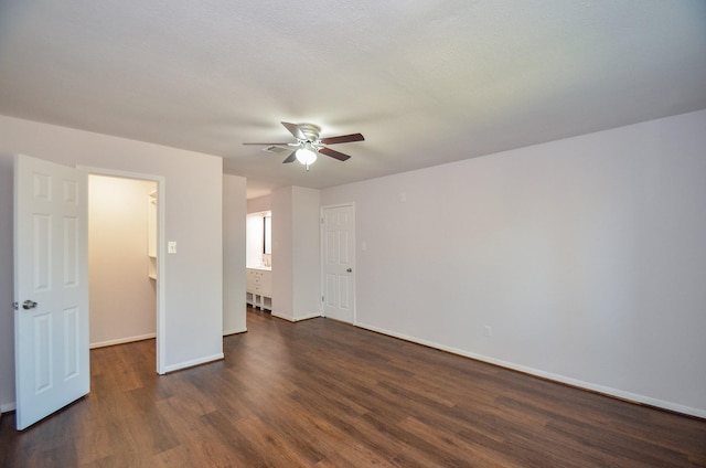 unfurnished bedroom with a ceiling fan, dark wood-style floors, baseboards, and connected bathroom