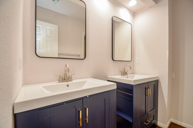 bathroom featuring a sink, visible vents, baseboards, and two vanities