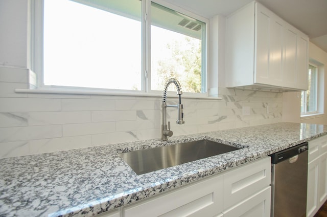 kitchen featuring dishwasher, white cabinets, tasteful backsplash, and a sink