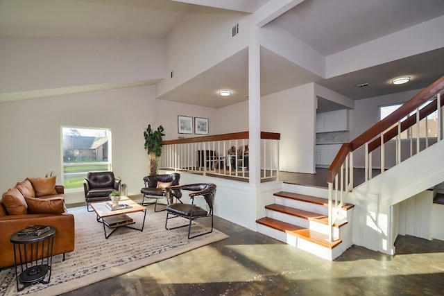 living room featuring stairway, visible vents, and finished concrete flooring