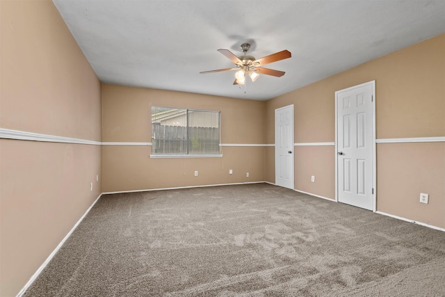 carpeted empty room with baseboards and a ceiling fan