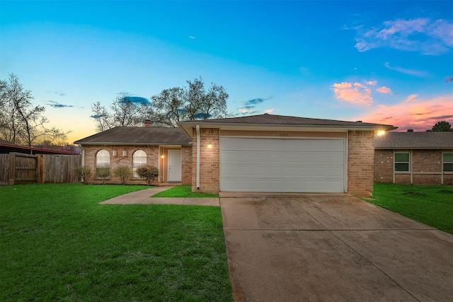 ranch-style house featuring a lawn, concrete driveway, brick siding, and fence