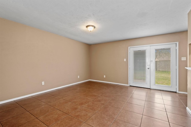 spare room with light tile patterned floors, french doors, a textured ceiling, and baseboards