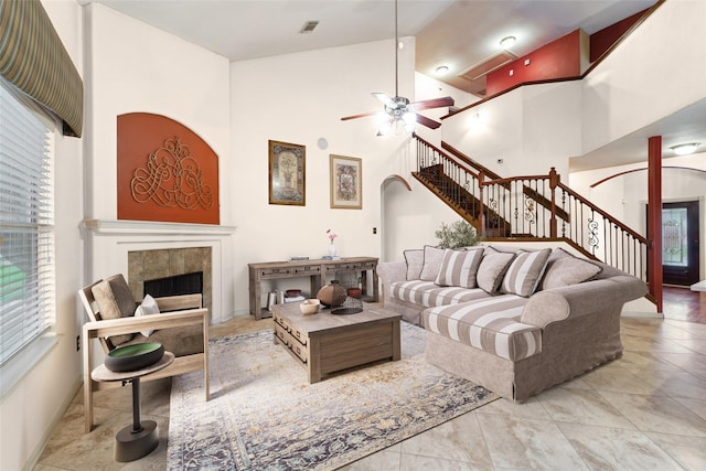 living room with visible vents, high vaulted ceiling, stairway, arched walkways, and a tile fireplace