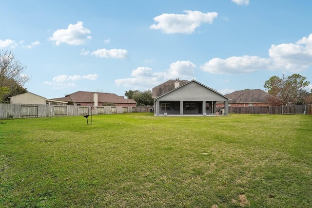 back of house with a yard and a fenced backyard