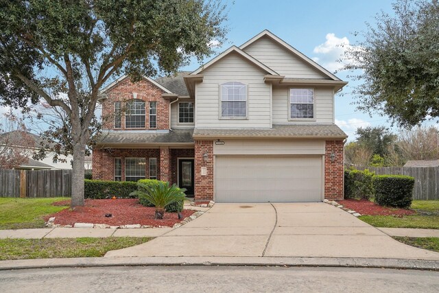 traditional-style home featuring brick siding, concrete driveway, an attached garage, and fence