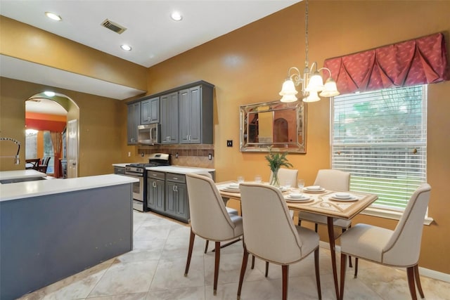 kitchen featuring visible vents, arched walkways, a sink, gray cabinetry, and stainless steel appliances