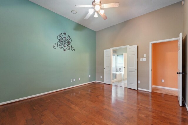 unfurnished bedroom with ceiling fan, baseboards, wood finished floors, and ensuite bathroom