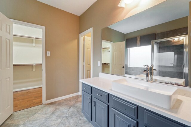 bathroom featuring a spacious closet, a shower stall, vanity, and baseboards