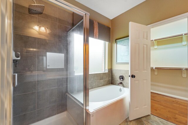 bathroom featuring a spacious closet, a bath, and a stall shower