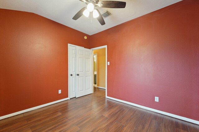 spare room featuring wood finished floors, visible vents, baseboards, ceiling fan, and vaulted ceiling