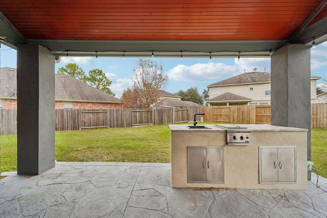 view of patio / terrace featuring a sink, a fenced backyard, and an outdoor kitchen