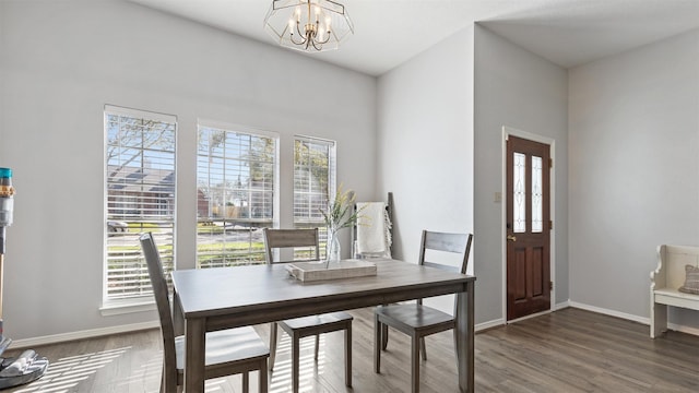 dining room featuring a chandelier, baseboards, and wood finished floors