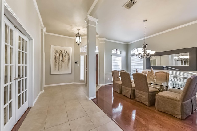 dining area featuring visible vents, crown molding, baseboards, a chandelier, and ornate columns