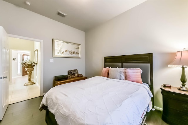 bedroom with wood finished floors, visible vents, and baseboards