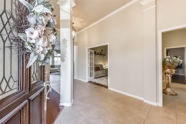 tiled foyer featuring crown molding, baseboards, and ornate columns