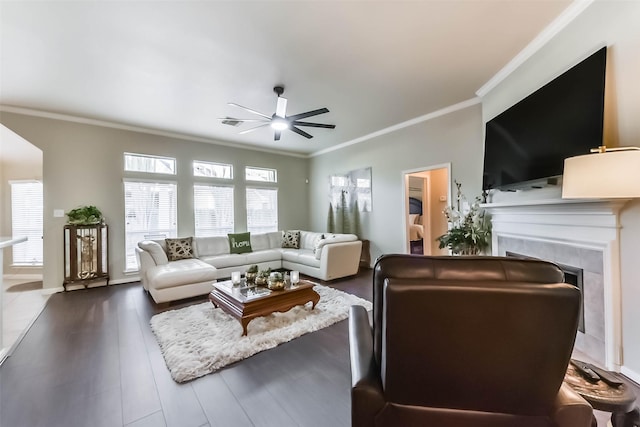 living room with ceiling fan, dark wood finished floors, ornamental molding, and a fireplace