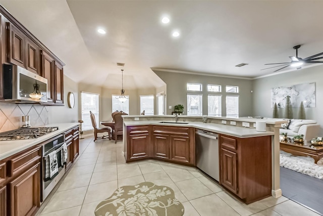 kitchen featuring tasteful backsplash, light countertops, light tile patterned floors, appliances with stainless steel finishes, and a sink