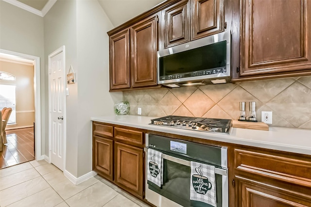 kitchen with backsplash, baseboards, light countertops, light tile patterned floors, and appliances with stainless steel finishes