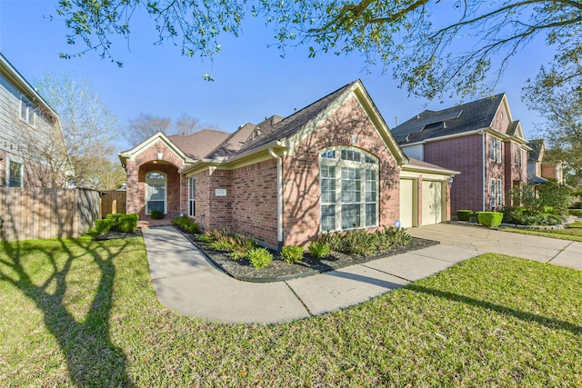 view of front of property featuring driveway, fence, a front yard, a garage, and brick siding