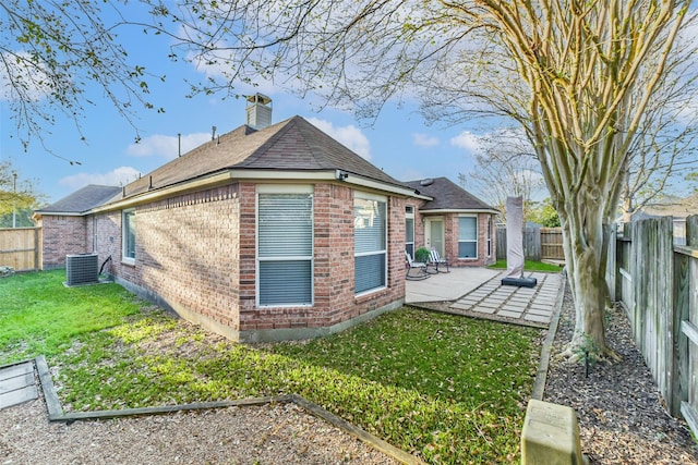 view of side of home featuring brick siding, central AC, a yard, a fenced backyard, and a patio area