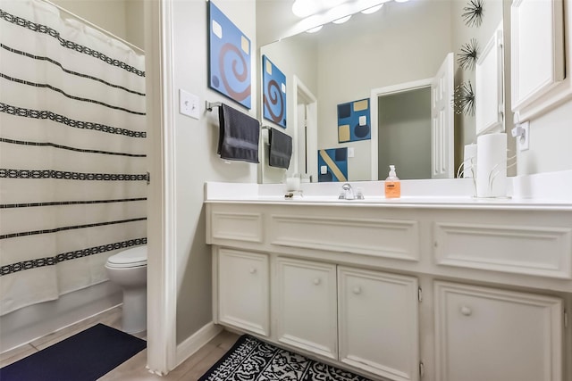 bathroom featuring curtained shower, toilet, vanity, and baseboards