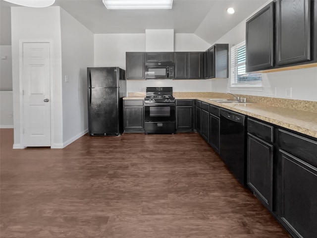 kitchen with baseboards, a sink, black appliances, vaulted ceiling, and light countertops