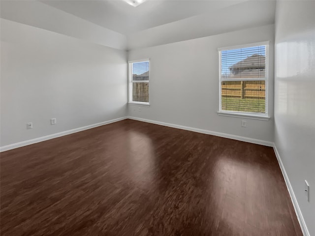 spare room featuring dark wood-type flooring and baseboards