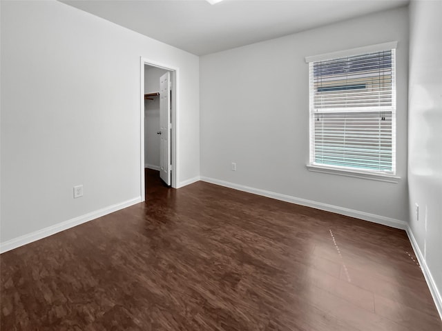 spare room featuring dark wood-style floors and baseboards