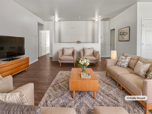 living room featuring visible vents, baseboards, and wood finished floors