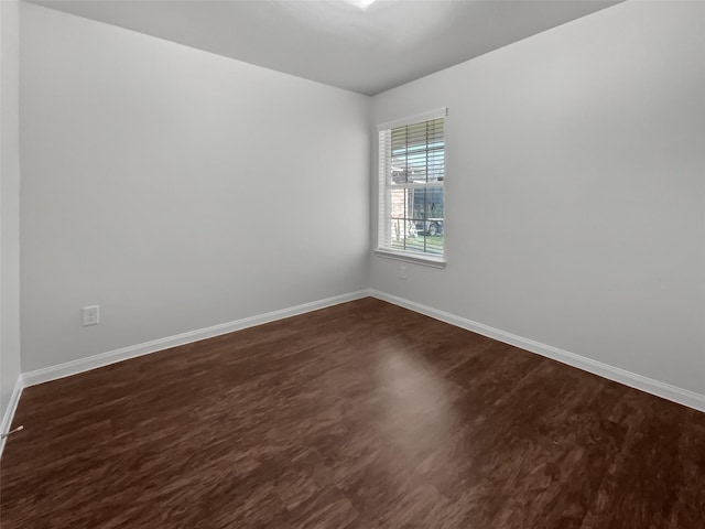 spare room with dark wood-type flooring and baseboards