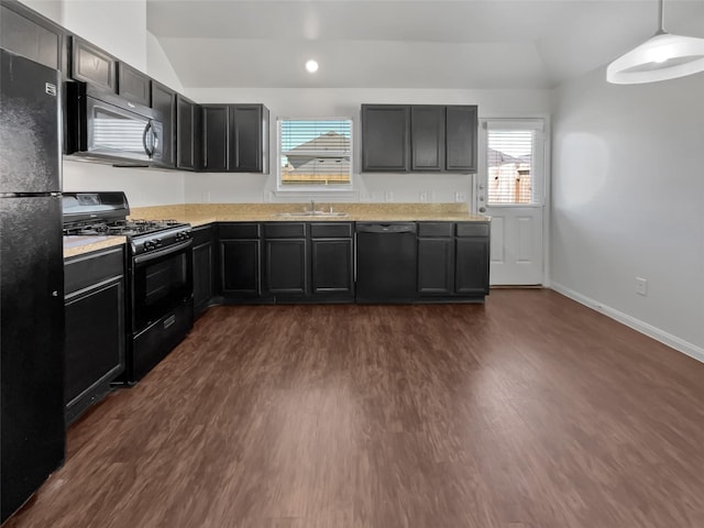 kitchen with black appliances, a sink, dark wood-style floors, light countertops, and vaulted ceiling