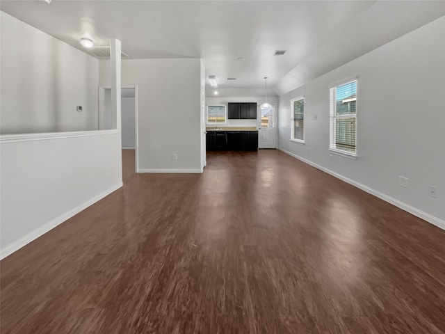 unfurnished living room with baseboards and dark wood-type flooring