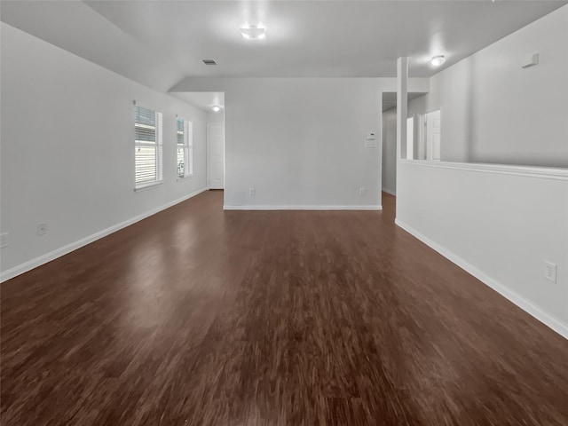 empty room with visible vents, baseboards, dark wood finished floors, and vaulted ceiling